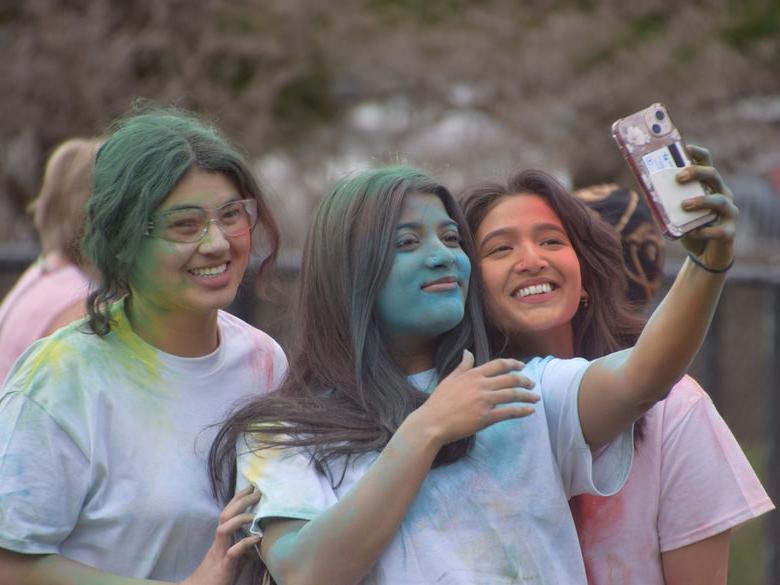 三个学生微笑着对着手机拍照